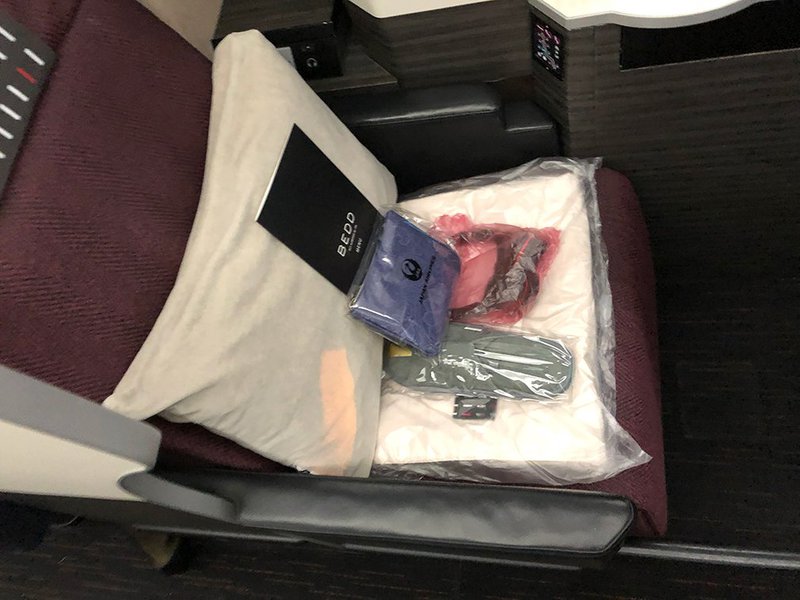 You will find your Sky Suites seat neatly stacked with all of your menu, blankets, noise canceling headphones and amenity kit.